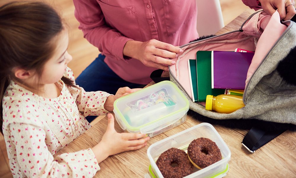 A mother and daughter packing a lunchbox and school bag together